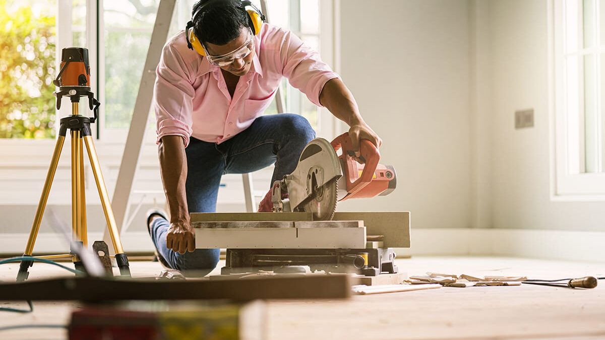 a man cutting wood as he undergoes summer home improvement