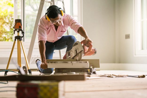 a man cutting wood as he undergoes summer home improvement