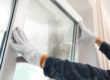 a person with gloves installs a window in a window replacement in winter
