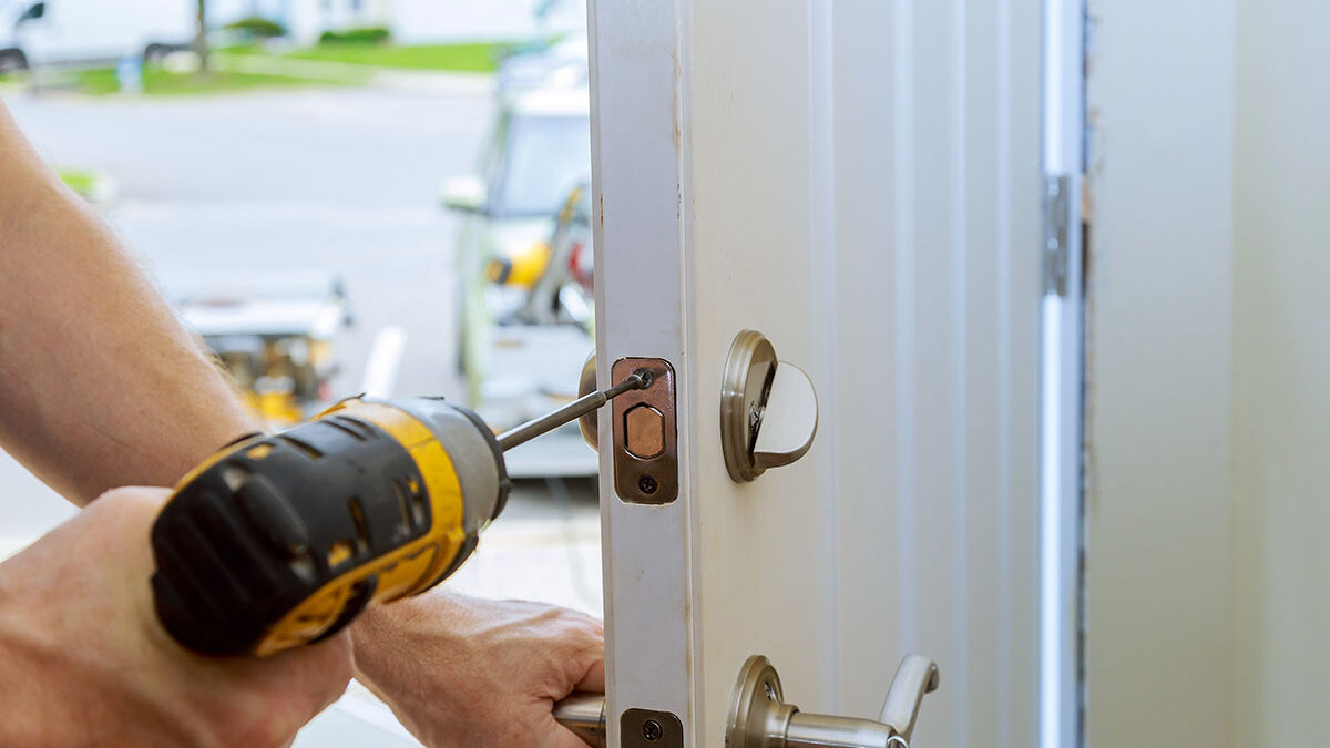 How Can I Get an Estimate for My Door Installation a person drills a lock into place possibly after giving a door installation estimate