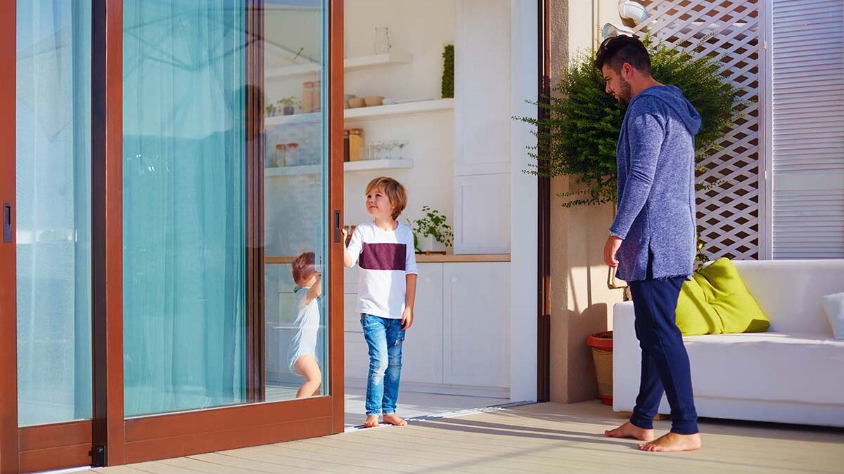 a beautiful modern sliding door is opened by a child out onto a patio to show sliding door trends
