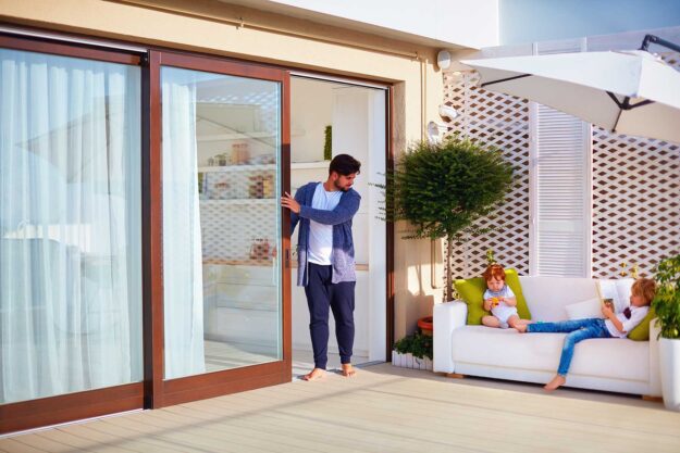 Sliding Door Vs Hinged Door – What Style Is Better_ a man is happy he chose a sliding patio door for his home