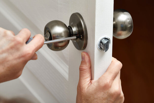 How to Clean Exterior Door Hardware a person reinstalls a doorknob after properly cleaning it