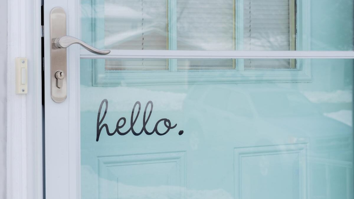 a newly replaced storm door with a hello decal