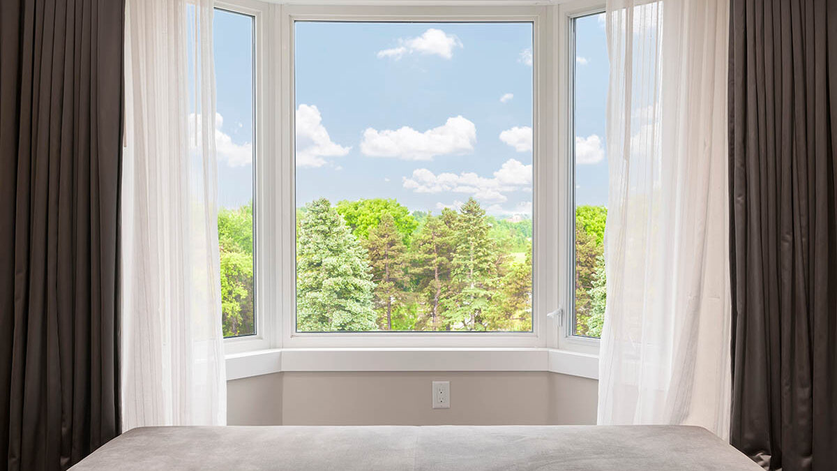 a homeowner has dressed their bay window with flowy curtains