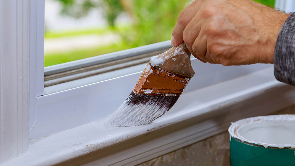 a professional paints the trim around a newly installed window