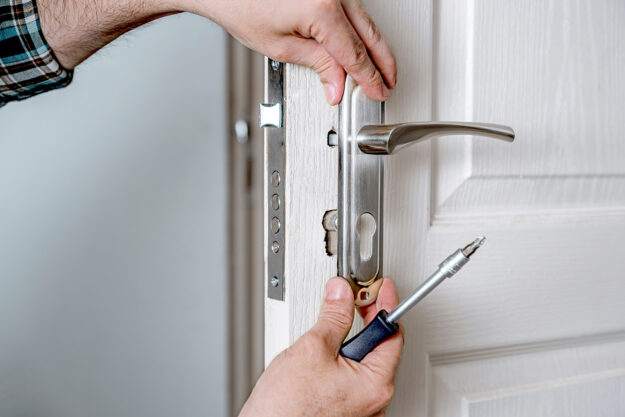 Finding-Door-Replacement-Services-In-Baltimore,-MD a person works on a door handle after a customer ordered a door replacement in baltimore md