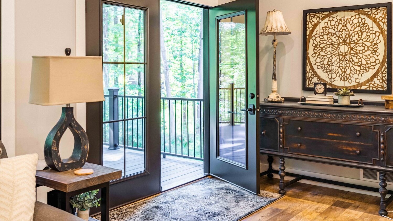 Living room interior with black French doors opening to a wooded deck.