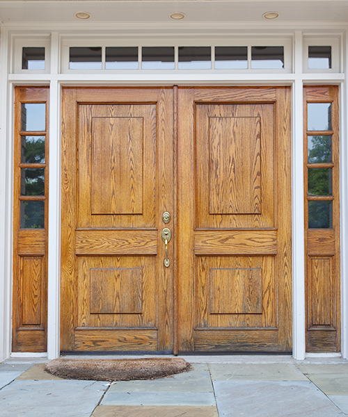 wooden double doors with sidelights on a white home
